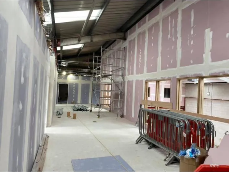 Boarded and taped fire rated corridor walls with framed window openings in a commercial fit out