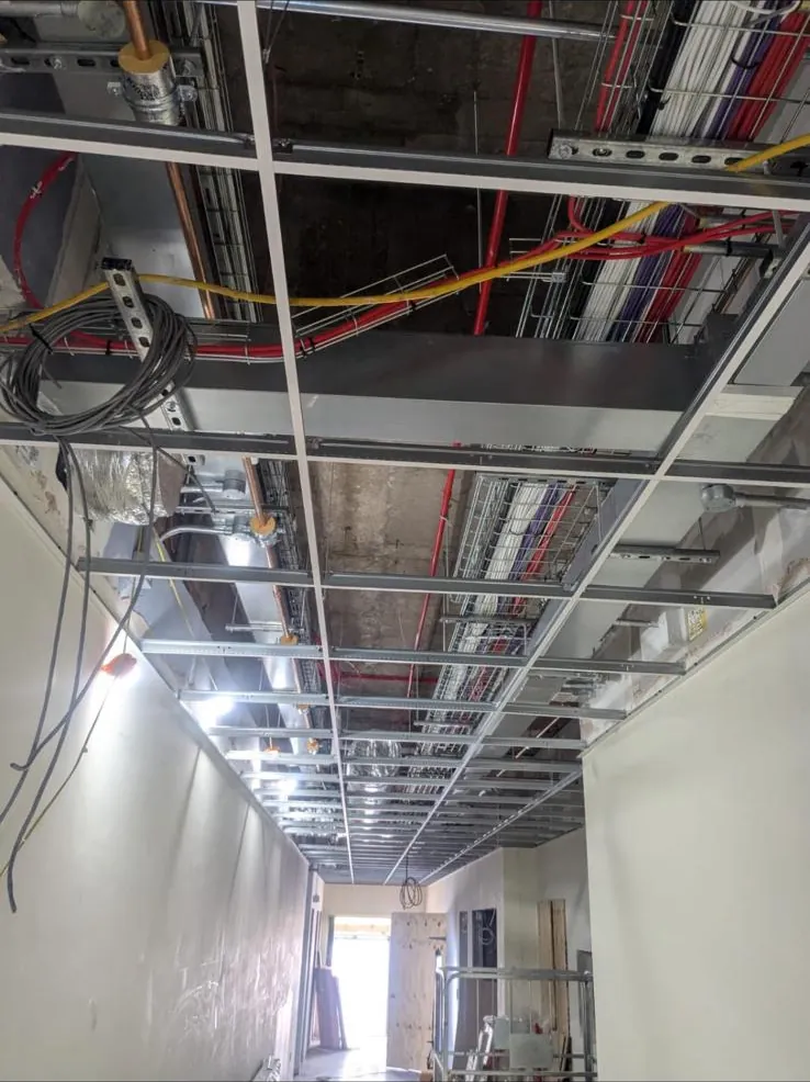 Ceiling grid running down a corridor beneath cable trays, pipework and ductwork