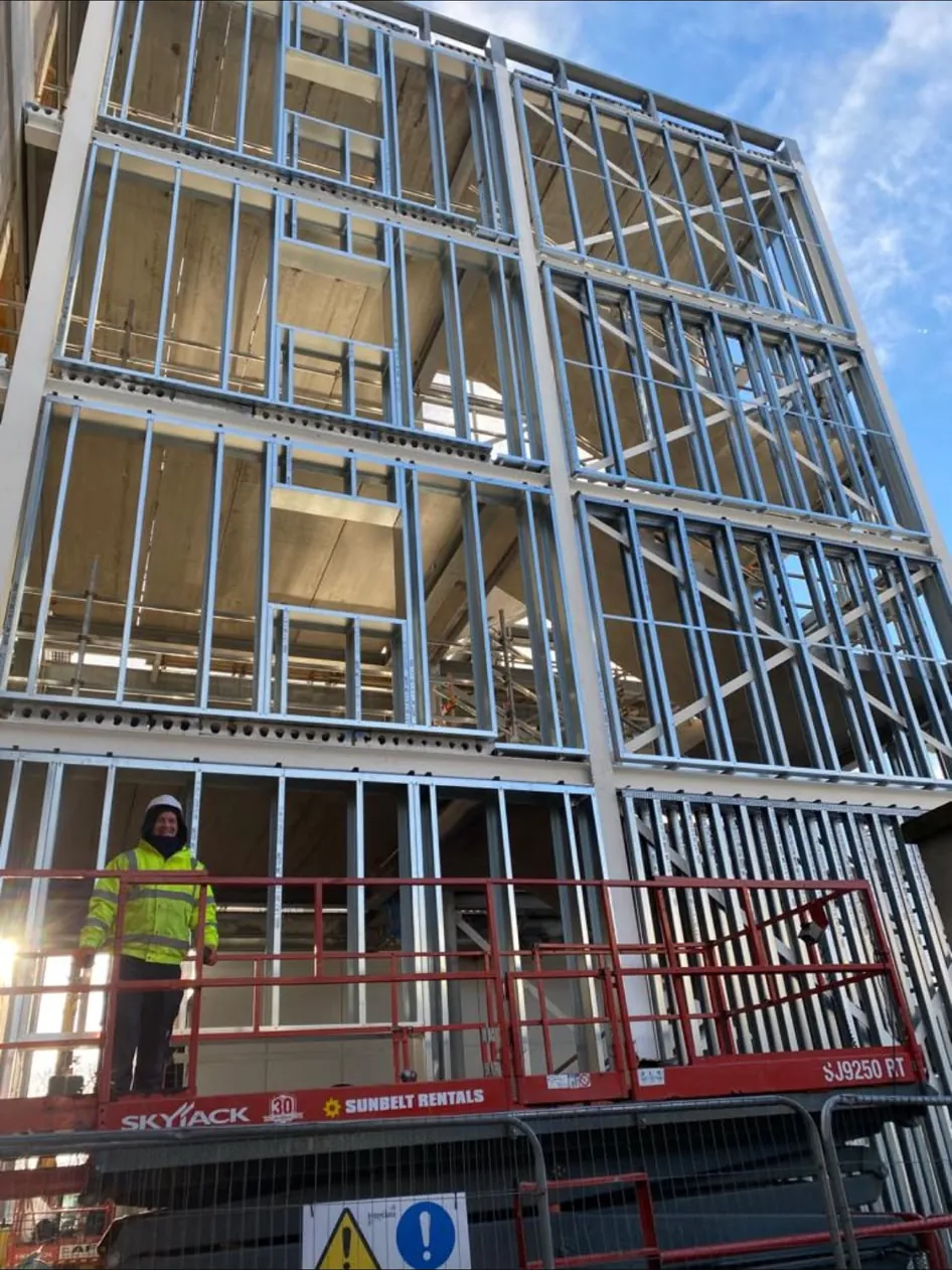 Multi storey SFS light gauge steel frame with a PAT Partitions fixer on a scissor lift at slab edge