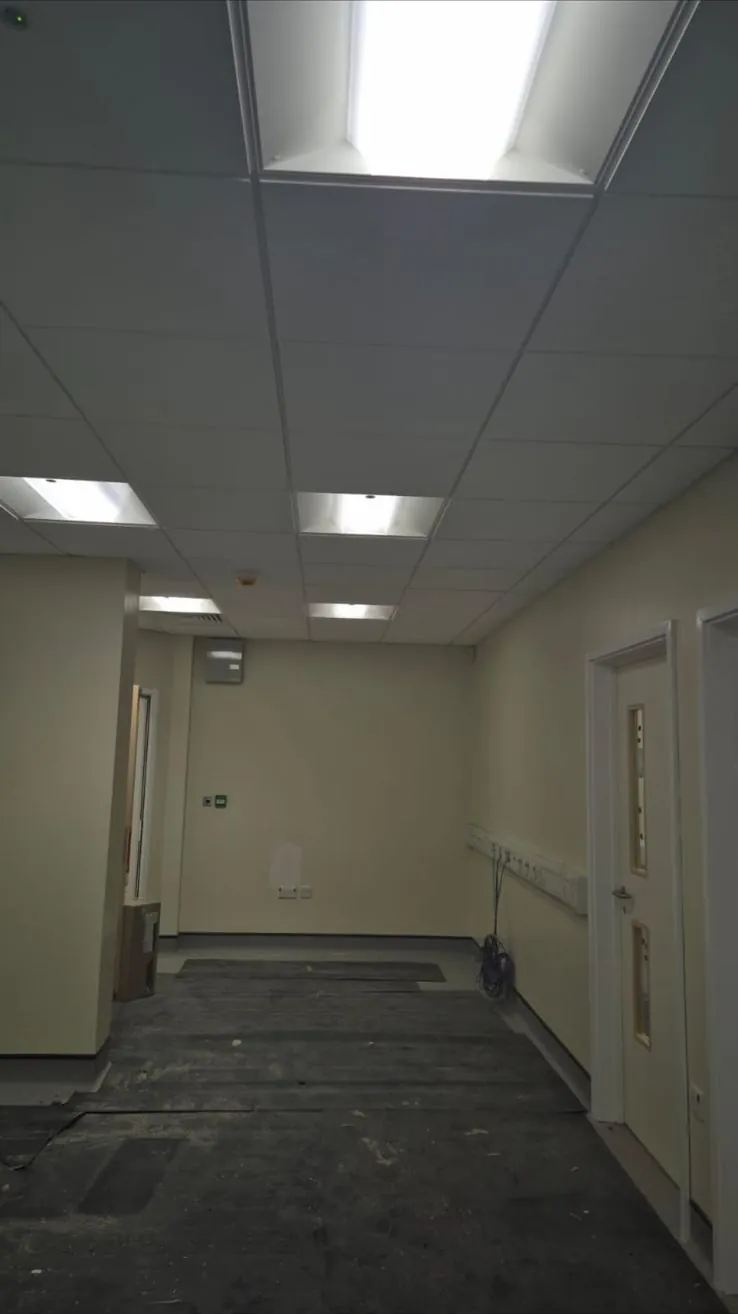 Finished hospital corridor with suspended ceiling, fire doors and skimmed walls