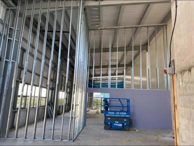 Full height metal stud partition framing in an industrial unit with a scissor lift